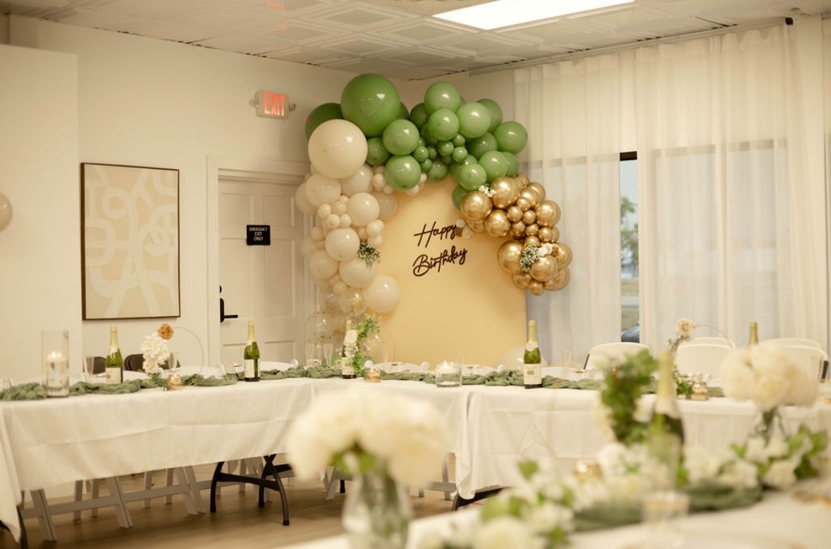 Gold hoop floral centerpiece with white flowers, greenery, and a gold votive candle.